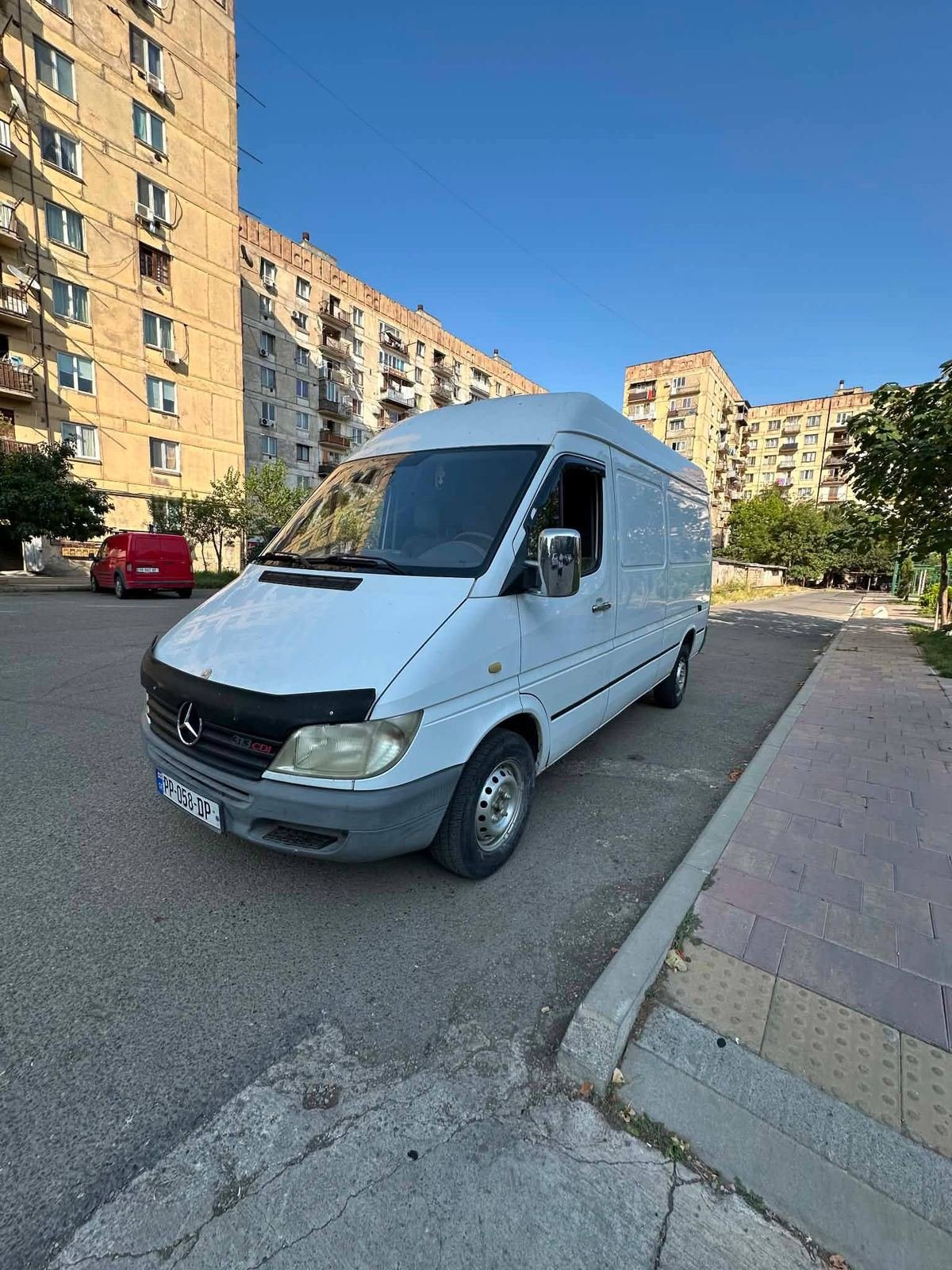 თეთრი დახურული სატვირთო ფურგონი ქალაქის ქუჩაზე